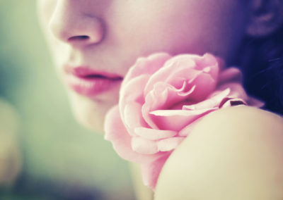 Woman pressing her cheek against a pink flower
